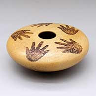 A polychrome seed pot decorated with a hand and splatter design above the shoulder, and a negative hand with splatter design below the shoulder
 by Garrett Maho of Hopi