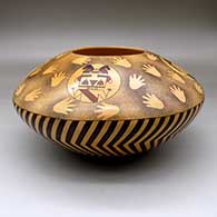 A large polychrome seed pot decorated above the shoulder with medallions of katsinas surrounded by splotches and handprints, and below the shoulder with a lightning bolt design
 by Garrett Maho of Hopi