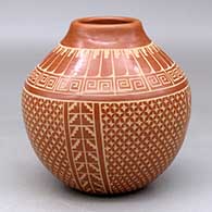 A red jar decorated with a sgraffito four-panel snowflake and geometric design below the shoulder and a feather, scroll and geometric design above the shoulder
 by Wilma Baca Tosa of Jemez