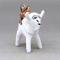 A polychrome figure with a little girl holding her younger sister and her drum on the back of a sacred white bison
 by Felicia Fragua of Jemez