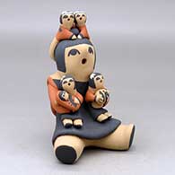 A sitting grandmother storyteller figure with four children on her
 by Vernida Toya of Jemez