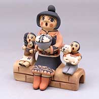 A Singing Mother figure sitting on an adobe wall with three children, a puppy and a pot
 by Chrislyn Fragua of Jemez