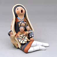 A sitting grandmother storyteller wearing a manta with four children, a drum and a welcome basket
 by Diane Lucero of Jemez