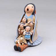 A sitting grandmother storyteller wearing a manta and skirt with four children, a puppy and a drum
 by Diane Lucero of Jemez