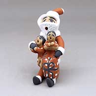 A sitting Santa Claus storyteller figure with two children and gifts
 by Felicia Fragua of Jemez