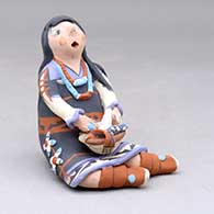 A Singing Mother figure, sitting with a welcome basket with ears of corn in her lap
 by Mary Lucero of Jemez