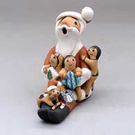 A sitting Santa Claus storyteller figure with three children, a puppy and gifts
 by Diane Lucero of Jemez