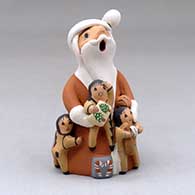 A standing Santa Claus storyteller figure with three children and gifts
 by Diane Lucero of Jemez