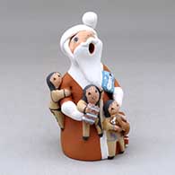A standing Santa Claus storyteller figure with three children and gifts
 by Diane Lucero of Jemez