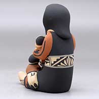 A sitting grandmother storyteller figure holding three children and a drum, click or tap to see a larger version