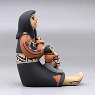 A sitting grandmother storyteller figure holding three children and a drum, click or tap to see a larger version