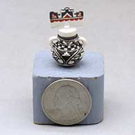 A miniature black on white jar with handles and a polychrome tablito lid and and decorated with a fineline, checkerboard and geometric design
 by Thomas Natseway of Laguna
