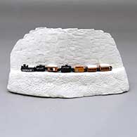 A white canyon wall with a polychrome miniature train running across the middle
 by Thomas Natseway of Laguna