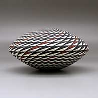 A polychrome seed pot decorated with a spiral mesa geometric design, click or tap to see a larger version