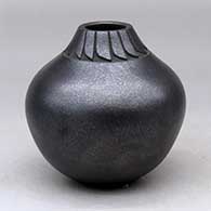A black micaceous jar decorated with a lightly carved band of feathers around the neck
 by Robert Vigil of Nambe