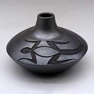 A micaceous black jar with a small neck and opening and decorated with a sgraffito lizard design above the shoulder
 by Robert Vigil of Nambe