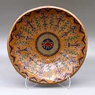 A shallow polychrome bowl decorated with a sgraffito and painted sun face, yeibichai, feathers and a geometric design
 by Nancy Yazzie of Dineh