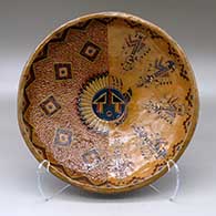 A shallow polychrome bowl decorated with a sgraffito and painted yeibichai, sun shield, feather and geometric design
 by Nancy Yazzie of Dineh