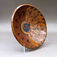 A wide, open polychrome bowl decorated inside with a sgraffito and painted Yeibichai, sun, feather, star and geometric design, and decorated outside with a geometric design, click or tap to see a larger version