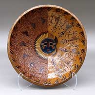 A wide, open polychrome bowl decorated inside with a sgraffito and painted Yeibichai, sun, feather, star and geometric design, and decorated outside with a geometric design
 by Nancy Yazzie of Dineh