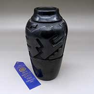 Tall black jar carved with a stylized avanyu design, First Prize ribbon NM State Fair 1969
 by Virginia Ebelacker of Santa Clara