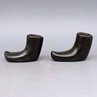 Two piece black candlestick holders in the shape of shoes
 by Reycita Cosen of Santa Clara