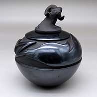 A black jar carved with an avanyu design and with a sculpted bighorn ram lid
 by Jeff Roller of Santa Clara