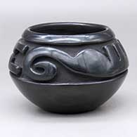 A black bowl decorated with a carved stylized avanyu design above the shoulder
 by Teresita Naranjo of Santa Clara