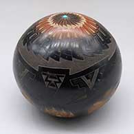 A black seed pot with sienna spots, an inlaid stone and a sgraffito bear paw, feather and geometric design
 by Justin Naranjo of Santa Clara