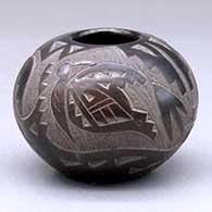 A small black jar with sienna spots and decorated with a sgraffito avanyu, butterfly and geometric design
 by Candelaria Suazo of Santa Clara