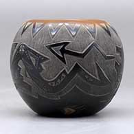 A small black bowl with a sienna rim and spots and decorated with a sgraffito avanyu, bear paw and geometric design, click or tap to see a larger version
