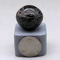 A miniature black seed pot decorated with a sgraffito avanyu, kiva step, lightning bolt and geometric design
 by Geri Naranjo of Santa Clara