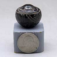 A miniature black seed pot decorated with a sgraffito avanyu, kiva step, lightning bolt and geometric design
 by Geri Naranjo of Santa Clara