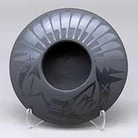 A black on black bowl decorated with an avanyu and feather design above the shoulder
 by Marvin and Frances Martinez of San Ildefonso