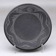 A black on micaceous black plate decorated with an avanyu and rain cloud geometric design
 by Johnny Cruz of San Ildefonso