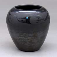 A black on black jar decorated with an avanyu with an inlaid stone and a cloud design above the shoulder
 by Johnny Cruz of San Ildefonso