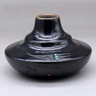 A black two-shouldered jar with a sienna rim, several inlaid stones and a sgraffito bat wing, spider and geometric design
 by Barbara Gonzales of San Ildefonso