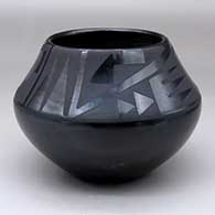 A black on black jar decorated with a two panel bat wing, kiva step and geometric design
 by Maria Martinez of San Ildefonso