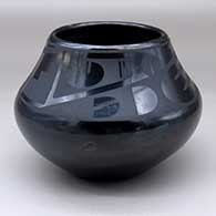 A black on black jar decorated above the shoulder with a two panel bat wing, kiva step and geometric design
 by Maria Martinez of San Ildefonso