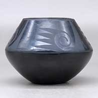 A black on black jar decorated above the shoulder with a four-panel bat wing, spiral and geometric design, click or tap to see a larger version