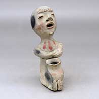 A polychrome Rain God with crossed arms, sculpted bangs and holding a pot in his lap
 by Unknown of Tesuque
