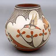 A polychrome jar decorated with a two panel hummingbird, butterfly, flower and geometric design with crosshatching
 by Marcellus Medina of Zia