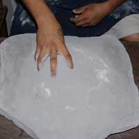 Hand mixing ground pottery shards into the clay powder